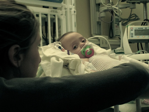 photo of an infant PFIC patient in a hospital bed with her mother looking on